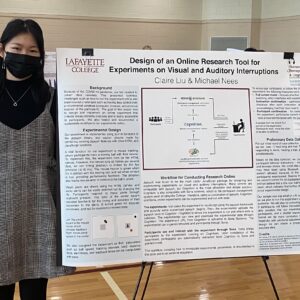 A student stands next to her poster at a poster presentation session.